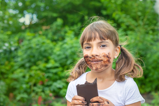 The child eats a chocolate bar. Selective focus. People. - Foto, imagen