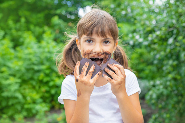Het kind eet een reep chocola. Selectieve focus. Mensen. - Foto, afbeelding