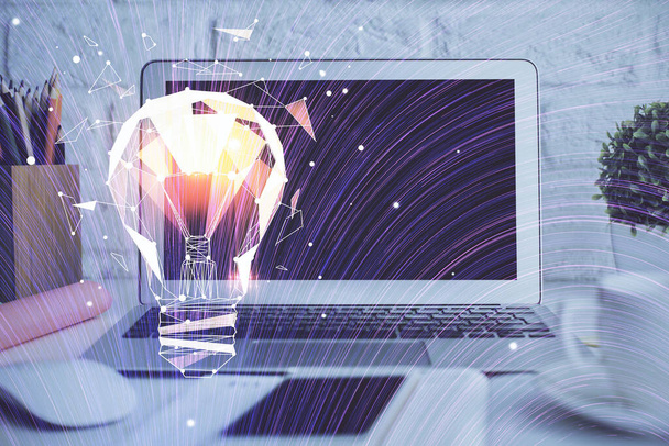 Computer on desktop in office with bulb icon hologram. Double exposure. Concept of idea. - Φωτογραφία, εικόνα