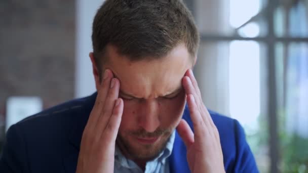 Young man suffering from headache in office - Video, Çekim