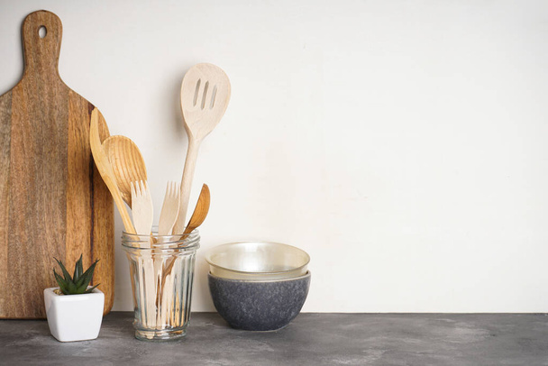 Wooden kitchen utensils in a glass on a gray background with place for text. - Foto, Bild