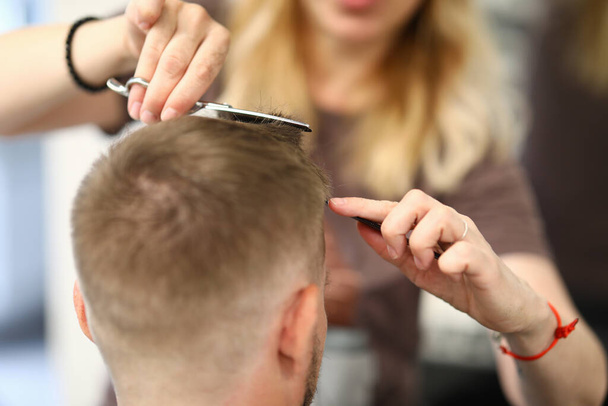 Woman hairdresser cuts mans hair in a beauty salon - Фото, изображение