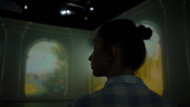 Mujer joven mirando a su alrededor en la exposición inmersiva - instalación de videoarte - Metraje, vídeo