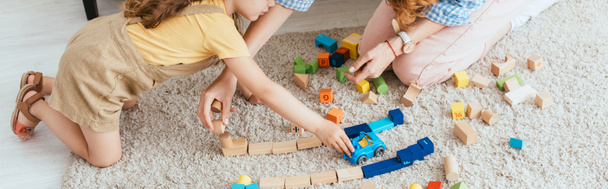 cropped view of nanny and child playing with multicolored blocks and toy car on floor, horizontal image - Photo, image
