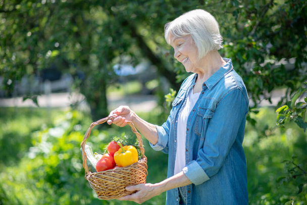 Elderly woman enjoying fresh and ripe vegetables - Foto, Imagen