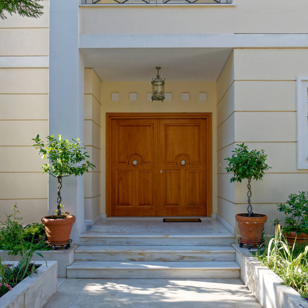Αθήνα Ελλάδα, σύγχρονη είσοδος σπιτιού ξύλινη πόρτα και δύο γλάστρες - Φωτογραφία, εικόνα