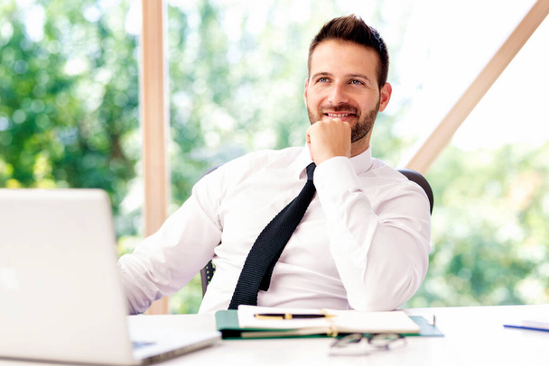 Successful businessman wearing a shirt and tie while sitting at office desk and working.  - Foto, afbeelding
