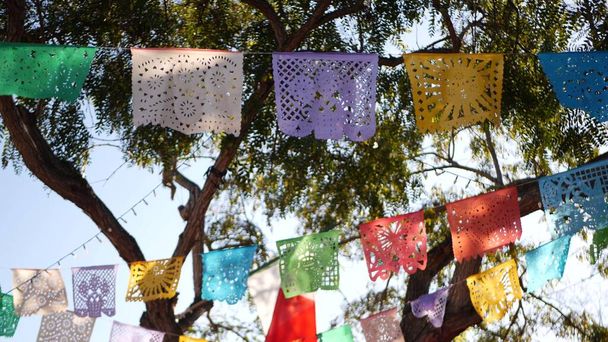 Разноцветный мексиканский перфорированный бумажный баннер, праздничная красочная бумажная гирлянда. Разноцветные латиноамериканские народные вырезанные тканевые флаги, праздник или карнавал. Аутентичная фиеста в Латинской Америке. - Фото, изображение