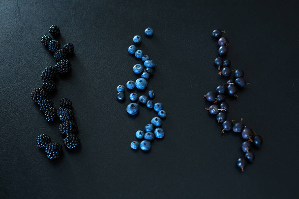 Mix set layout of different types of black berries on a black table. Stylish seasonal vitamins. - Photo, Image