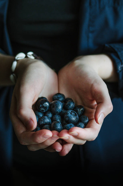 Une poignée de bleuets frais de près. Fille avec les mains pleines de baies noires mûres - Photo, image
