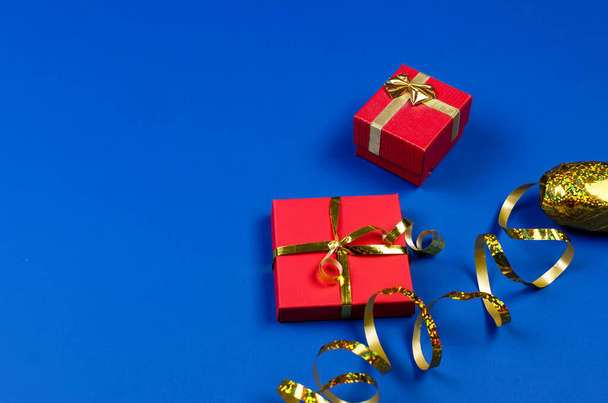 Two red gift boxes with golden ribbon on blue background. Top view, copy space, mock up, flat lay. Christmas, new year, Birthday, holiday. Festive background.  - Фото, зображення