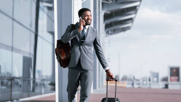 Afroamerikanischer Unternehmer telefoniert bei der Ankunft am Flughafen, Panorama - Foto, Bild