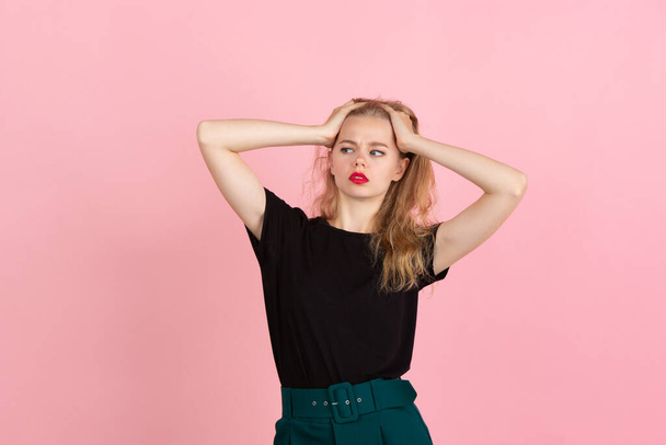 Young emotional woman on pink studio background. Human emotions, facial expression concept. - Foto, afbeelding