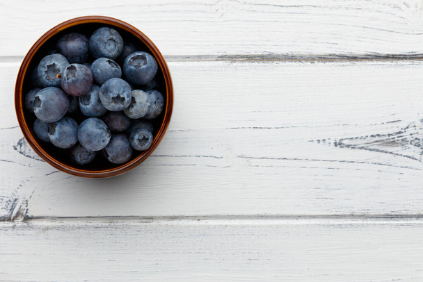 blueberries in a bowl on a distressed white wooden background with space for copy - Photo, Image
