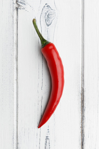 single red chilli on a distressed white wooden background - Foto, Bild