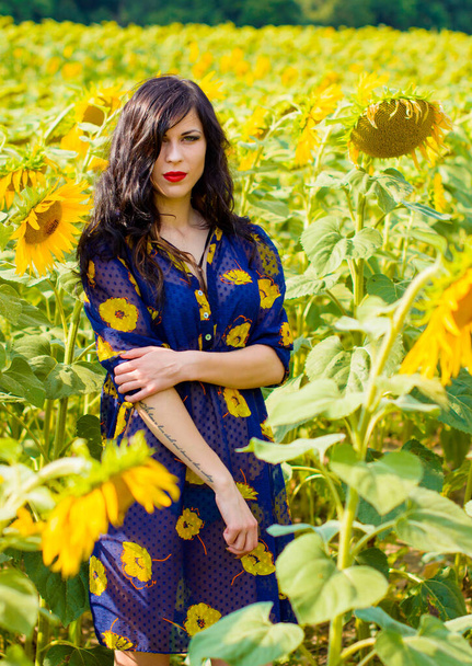 Atractiva joven morena rizada mujer en un prado de girasoles, en un campo de oro en buen día soleado tener un placer la vida
 - Foto, Imagen