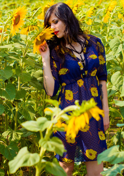 Atractiva joven morena rizada mujer en un prado de girasoles, en un campo de oro en buen día soleado tener un placer la vida
 - Foto, Imagen
