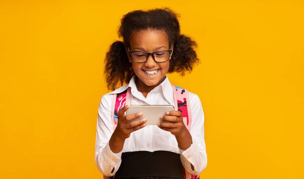 African Elementary School Girl Using Phone Playing Games In Studio - Фото, изображение