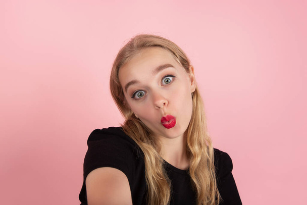Young emotional woman on pink studio background. Human emotions, facial expression concept. - Fotó, kép
