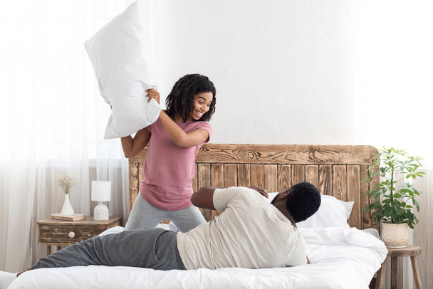 feliz casal negro tendo travesseiro luta pela manhã
 - Foto, Imagem