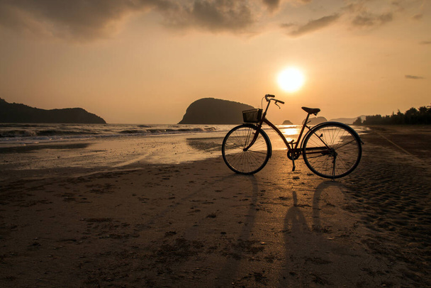 Sahilde bisiklet silueti, plajda gün batımında bisiklet ya da güneş ışığı - Fotoğraf, Görsel