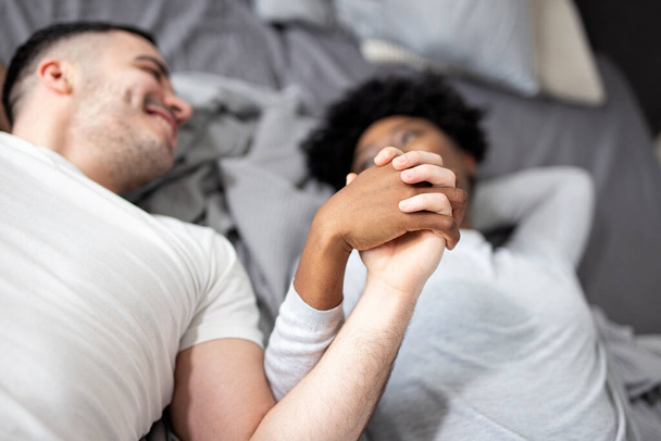 Пара в піжамах в ліжку тримає руки
 - Фото, зображення