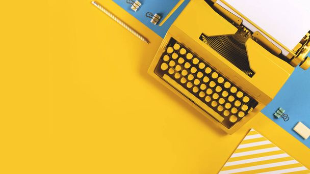 Keltainen kirkas kirjoituskone keltaisella ja sinisellä taustalla. Symboli kirjoittamiseen, bloggaamiseen, uusiin ideoihin ja luovuuteen. Kopioi tila - Valokuva, kuva