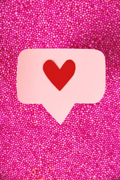 Rot wie ein Herz auf einer rosa Nadel über rosa Kugeln. Viele Emoji-Herzen in sozialen Netzwerken - Foto, Bild