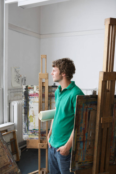 Young male artist looking out of the window in art studio - Fotoğraf, Görsel