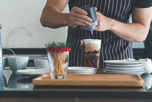 A kézről készült közeli kép frissen készült cappuccinót önt egy pohárba. barista Profi férfiak tejeskávét és eszpresszót készítenek az ügyfélszolgálatnak. A kávézó tulajdonosa italokat készít a kávézóban.. - Fotó, kép