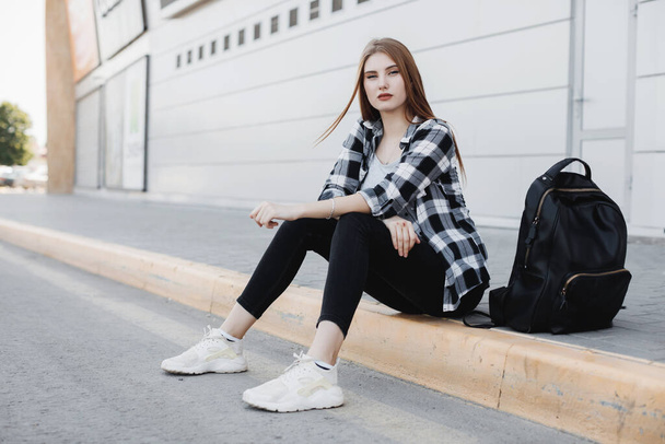Junge Modefrau sitzt draußen vor grauem Hintergrund - Foto, Bild