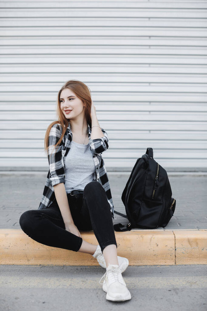 Young fashion woman sitting outdoors near gray background - Fotografie, Obrázek
