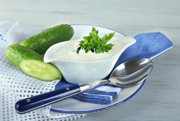 Cucumber yogurt in sauceboat, on color napkin, oncolor wooden background - Foto, afbeelding