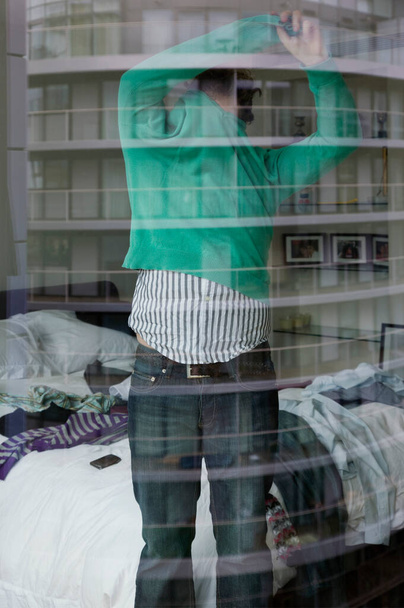 Man undressing in bedroom view through window - Fotoğraf, Görsel
