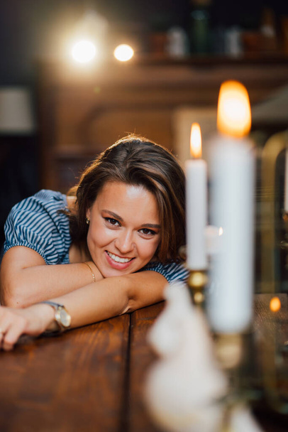 attractive brunette lay down on wooden table with candle on it. - Foto, Bild