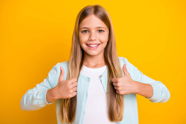 Photo of beautiful little blond lady model hold two arms raise thumb fingers advising approving good sale products select pick wear casual blue shirt isolated yellow bright color background - Фото, изображение
