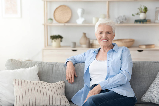 Rento iäkäs nainen poseeraa sohvalla Im kodikas sisustus - Valokuva, kuva
