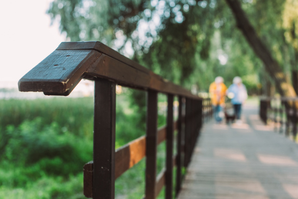 Selective focus of wooden bridge and couple walking in park  - Foto, Imagem