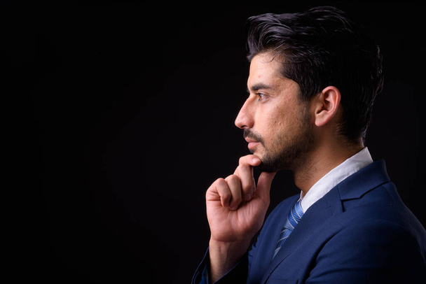 Studio shot of young handsome bearded Persian businessman against black background - Foto, Bild