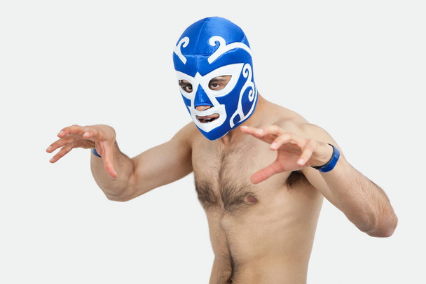 Portrait of a shirtless man in wrestling mask gesturing over gray background - Фото, изображение