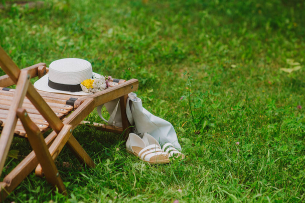 Chapéu de vime de algodão e saco ecológico perto de cadeira de plataforma de madeira
 - Foto, Imagem