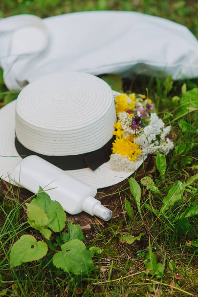 Sunscreen lotion, cotton woven hat and eco bag lying on green grass - Photo, Image