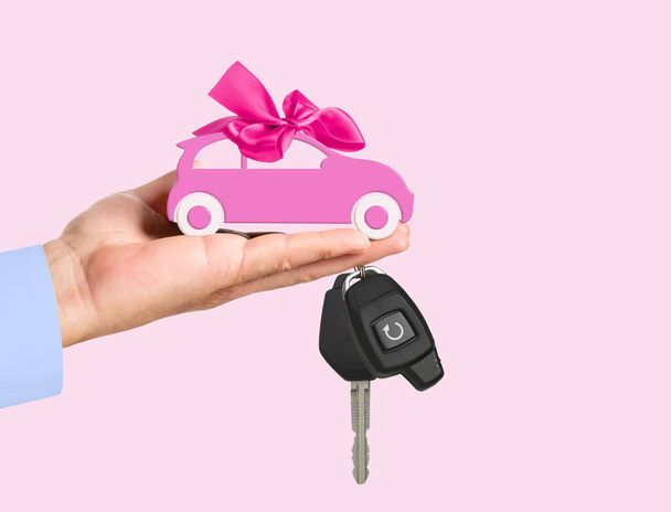 Автомобиль с луком и ключом на дилеров пальмы изолированы на розовом фоне. - Фото, изображение