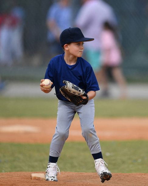 Akční fotografie pohledný mladý baseballový hráč dělat úžasné hry během baseballové hry - Fotografie, Obrázek