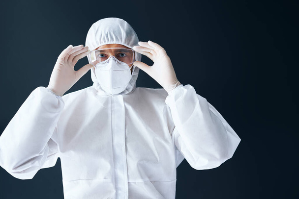Doctor in PPE wearing protective glasses on black background - Φωτογραφία, εικόνα