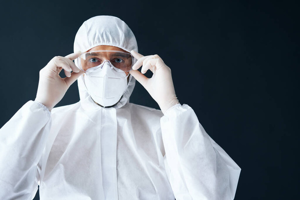 Doctor in PPE wearing protective glasses on black background - Foto, afbeelding