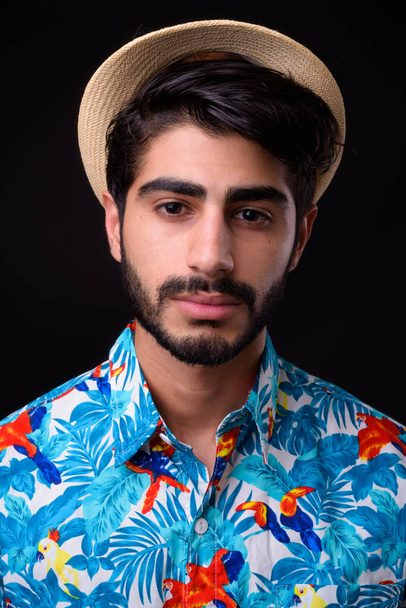 Studio shot of young handsome bearded Persian tourist man ready for vacation against black background - Zdjęcie, obraz