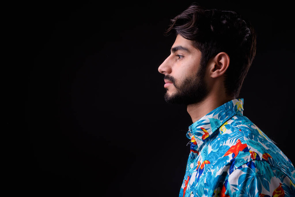 Estudio disparo de joven guapo barbudo turista persa listo para las vacaciones sobre fondo negro - Foto, Imagen