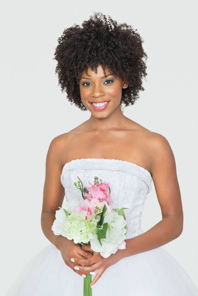 Portrét atraktivní afroamerické nevěsty držící kytici na šedém pozadí - Fotografie, Obrázek