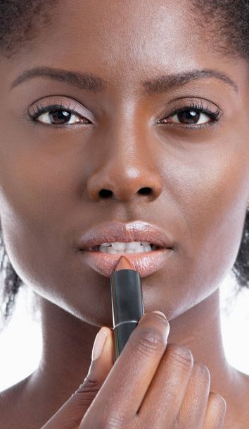 Close-up portrait of young African American woman applying lipstick - Fotó, kép